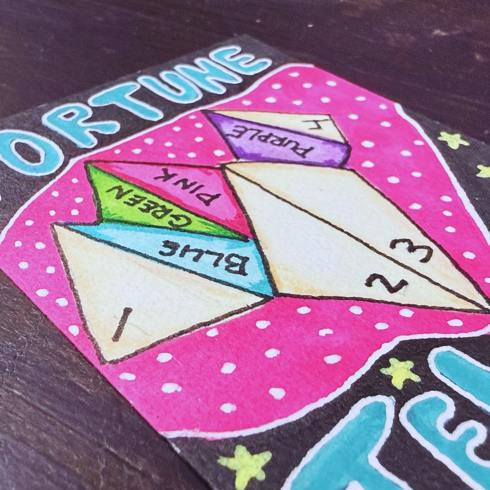 Colorful fortune teller toy with labeled sections on a dark surface