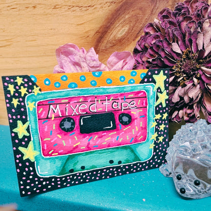 Colorful 'Mixed Tape' cassette design with decorative elements on a wooden surface.