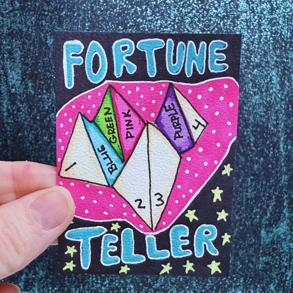 Colorful 'Fortune Teller' card with paper triangles and text on a textured blue background.