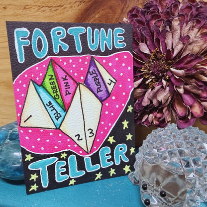 Fortune Teller card with colorful paper triangles and decorative elements on a wooden surface.